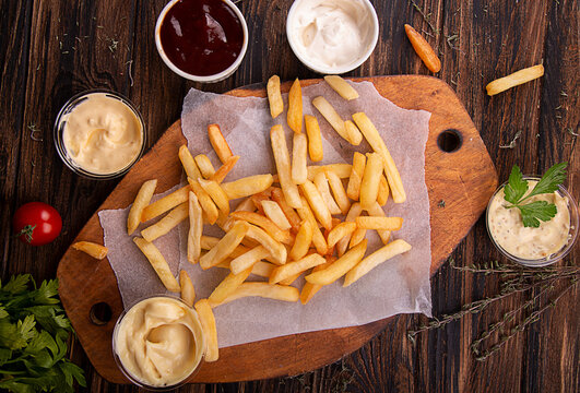 French fries chips potato and sauces on wooden background. top view
