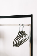 Black metal clothing rail with empty coat hangers in a white room. Close up.