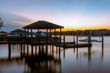 Fototapeta na wymiar The sun is setting and sky is almost clear of clouds at these Private docks in the Banks Channel near the Intracoastal Waterway in Wrightsville Beach, North Carolina