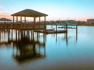 The sun is setting and sky is almost clear of clouds at these Private docks in the Banks Channel near the Intracoastal Waterway in Wrightsville Beach, North Carolina