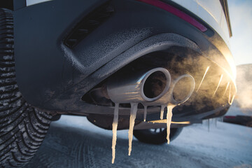 car exhaust pipe with icicle and smoke at shallow depth of field on a frosty day - obrazy, fototapety, plakaty