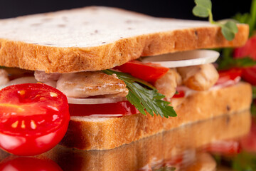 Sandwiches with chicken meat, cherry tomato, onion and chicken meat, marinated cucumbers, mozzarella cheese on  black background.