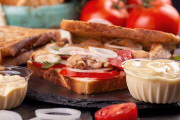 Ingredients and sandwiches with chicken meat, cherry tomato, onion and chicken meat, marinated cucumbers, mozzarella cheese on  black background. copy space