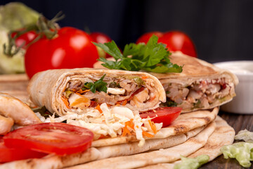 Popular arabic turkish fastfood doner shawarma roll with meat and vegetables and ingredients on dark background
