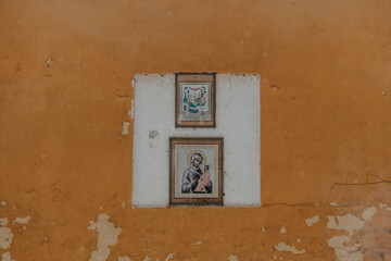 Icons with saints, virgin mary and baby jesus, on the street wall of an old house.