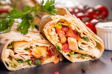 Popular arabic turkish fastfood doner shawarma roll with meat and vegetables on dark background