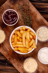 French fries chips potato and sauces on wooden background. top view