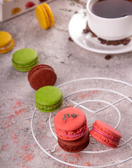 colorful macarons and cup of coffee over on gray background.