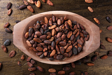Raw cocoa beans inside wooden tray with rustic background top view