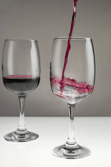 Red wine is poured from a bottle into a glass on a blurred background, close-up.