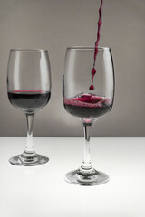 Red wine is poured from a bottle into a glass on a blurred background, close-up.