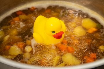 Yellow rubber duck swimming on the soup, duck stock, broth, Vegetable soup