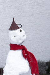 Funny snowman with a red scarf and a funnel as a hat