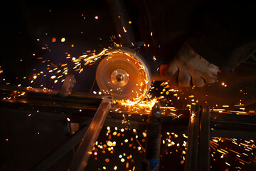 Sparks fly in all directions. Cutting metal with a grinder. Working in a metal workshop. Heating...