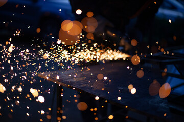 Sparks fly in all directions. Cutting metal with a grinder. Working in a metal workshop. Heating...