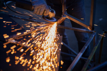 Sparks fly in all directions. Cutting metal with a grinder. Working in a metal workshop. Heating...