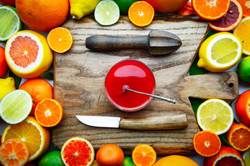 Mix of different citrus fruits and glass of juice with wooden board, squeezer and knife closeup. Healthy diet vitamin concept. Food photography