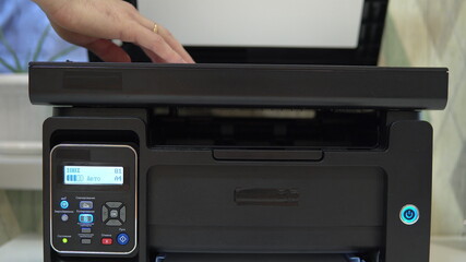 A man puts a document on the scanner to scan and tries to start