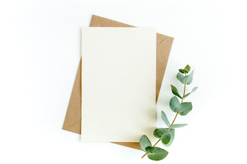 Mockup invitation, blank greeting card and green leaves eucalyptus. Flat lay, top view.