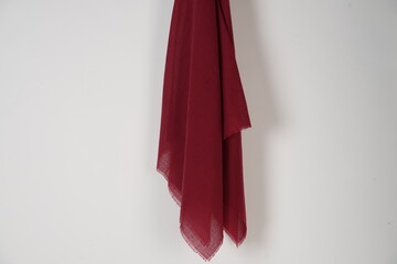 red scarf hung on the wall. Thin fabric texture is commonly used for fashion materials. Fabric mockup for a design template. Muslim veil is empty. Cloth that is attached to the nail on wall.