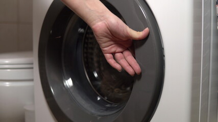 Girl loads dirty things into the washing machine close-up