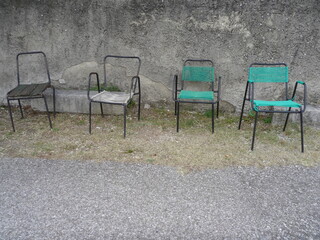 Vier leere Stühle vor einer grauen Mauer