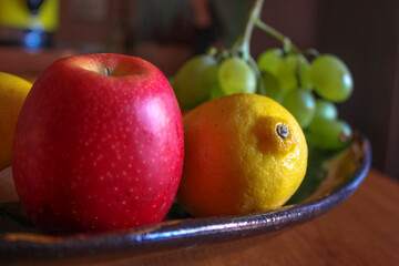 Still life of fresh seasonal fruit, ripe red apple, lemon and green grapes. High quality photo