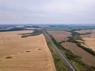 Drone aerial view of BR 373 road and farm field cultivated with soybean in rural area of Paraná state, Brazil, on summer day. Concept of agriculture, farming, ecology, food, work, economy, industry.
