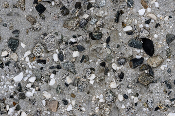 Concrete wall texture with pebbles. Decorative rough concrete surface with white, black and gray stones. Perfect for background and design. Closeup. High resolution.