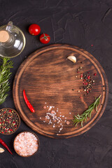 Round wooden cutting board on a black table. Top view of empty kitchen trendy rustic wooden tray.