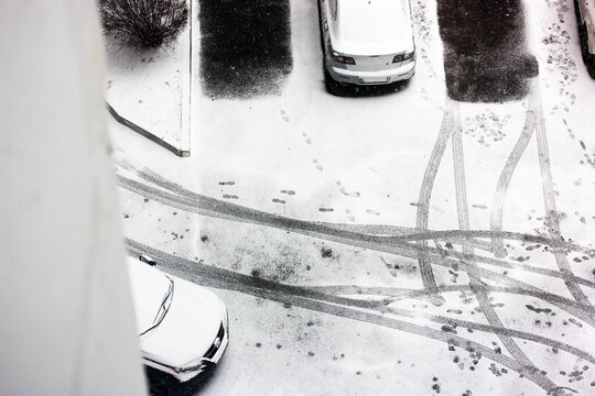 Cars covered with snow in the parking lot in winter, free parking space and tire tracks. View from above. High quality photo