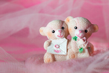 souvenir teddy bears on a pink textile background with hearts and flowers for Valentine's day