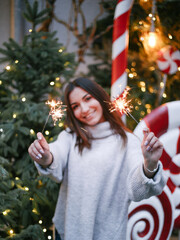 young woman smiling and celebrating new year and Christmas with sparklers. blurred