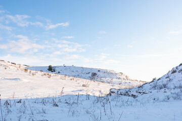 Fototapeta na wymiar Hilly snowy landscape with clear blue sky