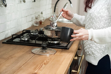 Woman cooking delicious mulled wine at stove closeup. process of making mulled wine at home in kitchen
