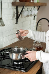 Woman cooking delicious mulled wine at stove closeup. process of making mulled wine at home in kitchen