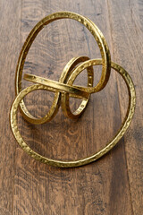 Gold metal torus infinity shape on dark hickory wood