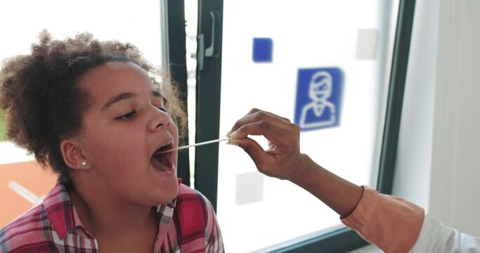 A Visit To A Child Patient By A Family Doctor, Pediatrician. A Girl Shows A Sore Throat To A Doctor By Opening Her Mouth. Checking The Health Of The Child. Admission To The Hospital