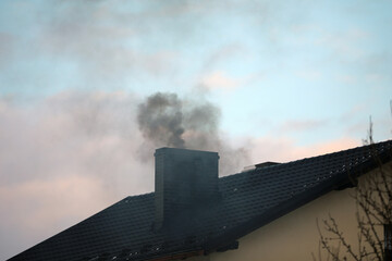 Dark smoke from a chimney from a single-family house - obrazy, fototapety, plakaty