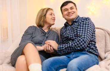 portrait of adult couple sitting on a sofa at home