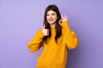 Young Ukrainian teenager girl over isolated purple background showing ok sign and thumb up gesture