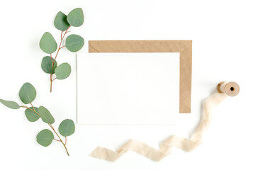 Mockup invitation, blank greeting card and green leaves eucalyptus. Flat lay, top view.