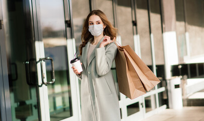 Young female wearing a mask for prevent virus with shopping bags on narrow street in Europe.