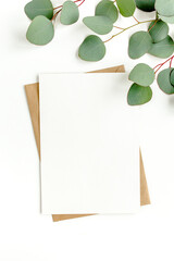 Mockup invitation, blank greeting card and green leaves eucalyptus. Flat lay, top view.