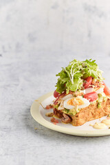 French toast stacked high and topped with salmon, lettuce, cheese, apple, whip cream and maple syrup in a warm, rustic, inviting restaurant atmosphere.