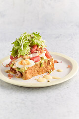 French toast stacked high and topped with salmon, lettuce, cheese, apple, whip cream and maple syrup in a warm, rustic, inviting restaurant atmosphere.