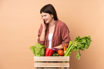 Young farmer girl with freshly picked vegetables in a box smiling a lot