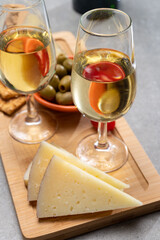 Glasses of dry fino sherry wine served with spanish tapas, manchego cheese, green olives, cheese crackers