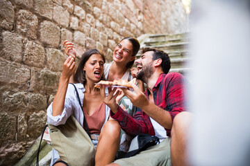 Friends eating slice of pizza at vacation