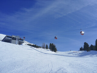 Leere Skipiste mit roten Gondel und Bergstation in Tirol
